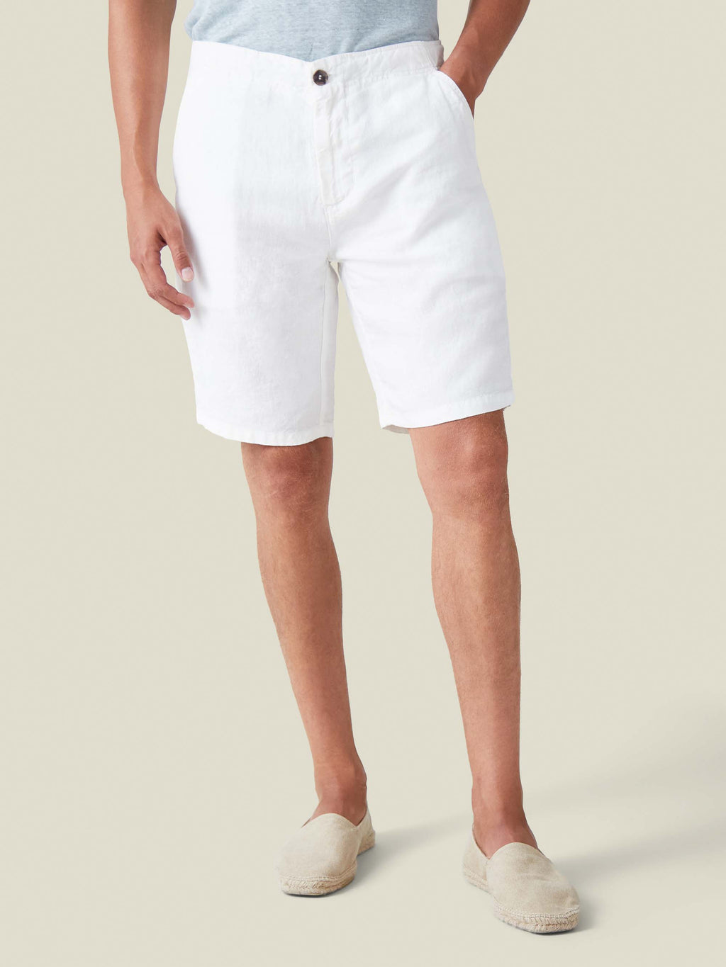 Front view of a model wearing Luca Faloni's white Bermuda linen shorts, styled with cream espadrilles.