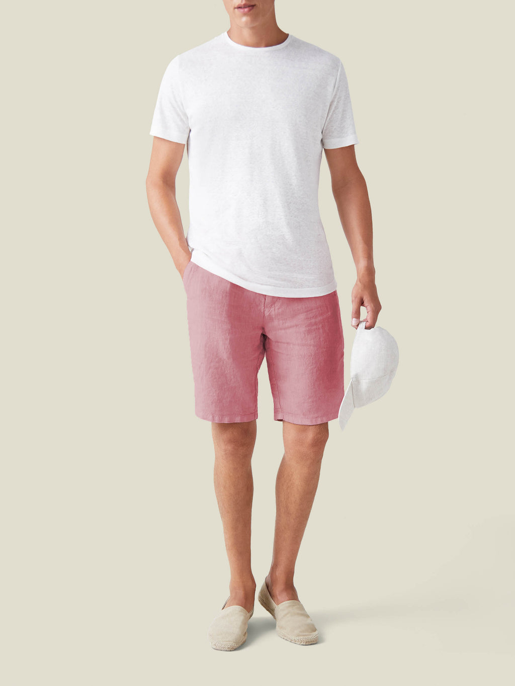 Full-length view of a model wearing Luca Faloni's Dusty Pink Bermuda Linen Shorts with a white t-shirt and loafers.
