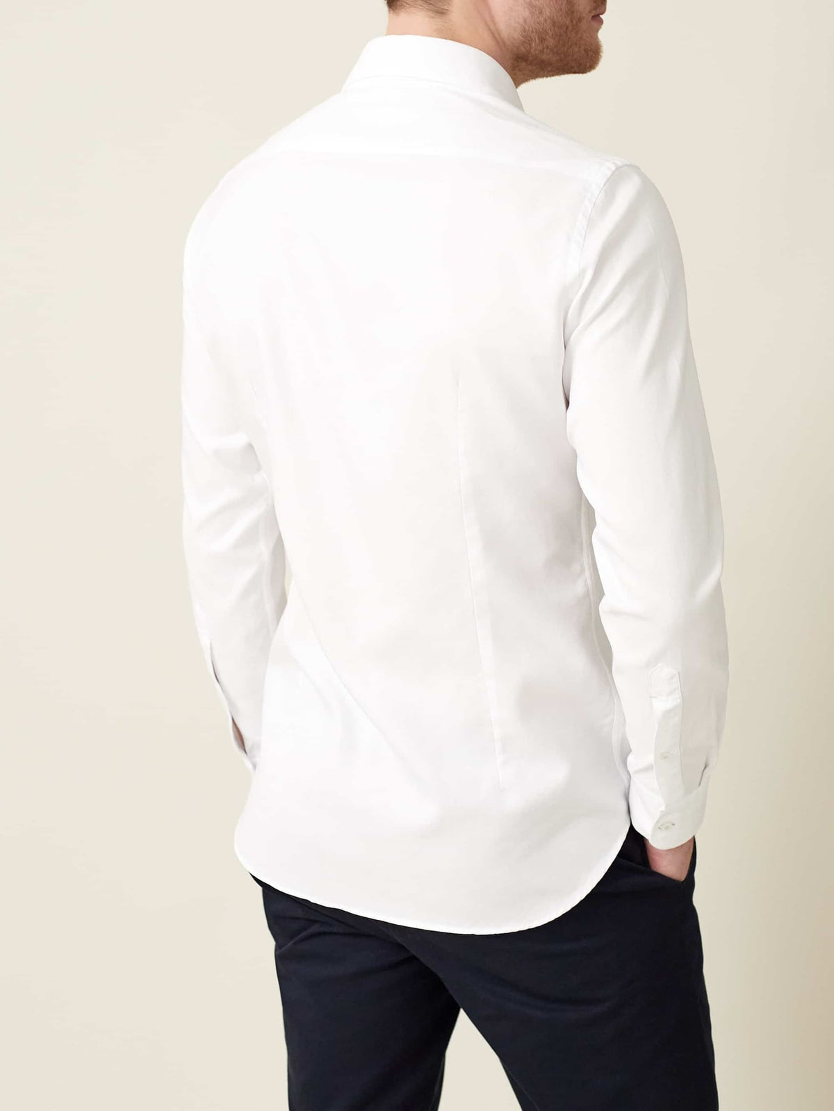 Model wearing the white Oxford Cotton Shirt, viewed from the back to showcase the shirt's slim fit and rounded hem.