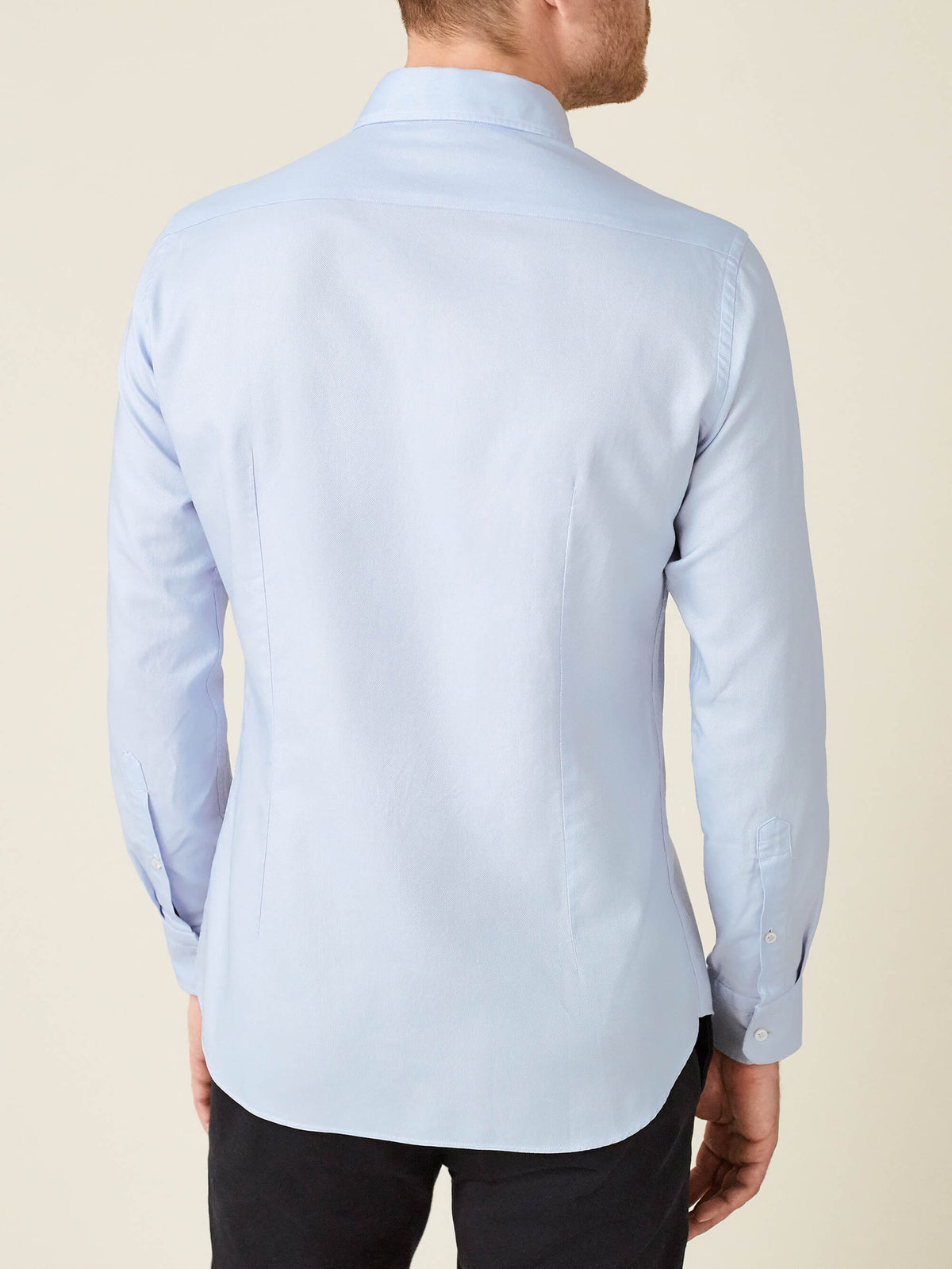 Back view of a model wearing the Light Blue Oxford Cotton Shirt, showcasing its elegant slim fit and tailoring details.