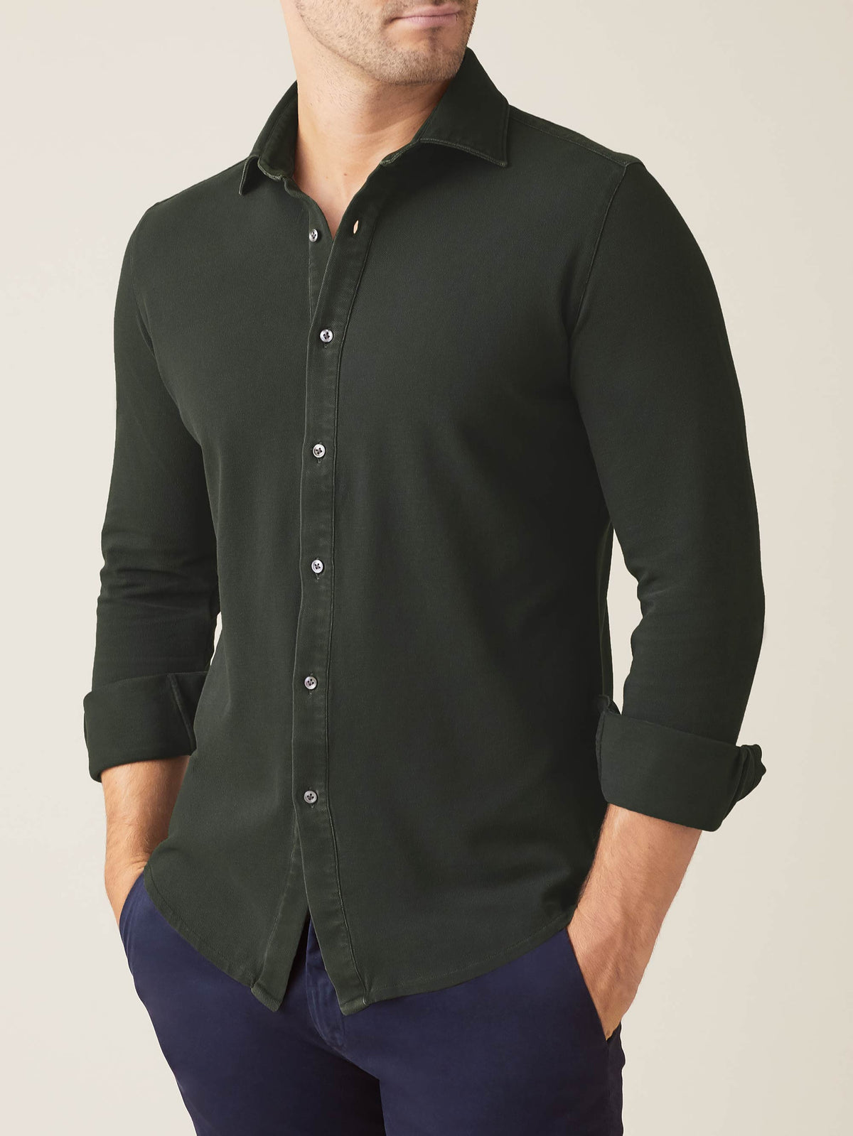 Front view of a model wearing the Siena Piqué Shirt in Forest Green with the sleeves casually rolled up.