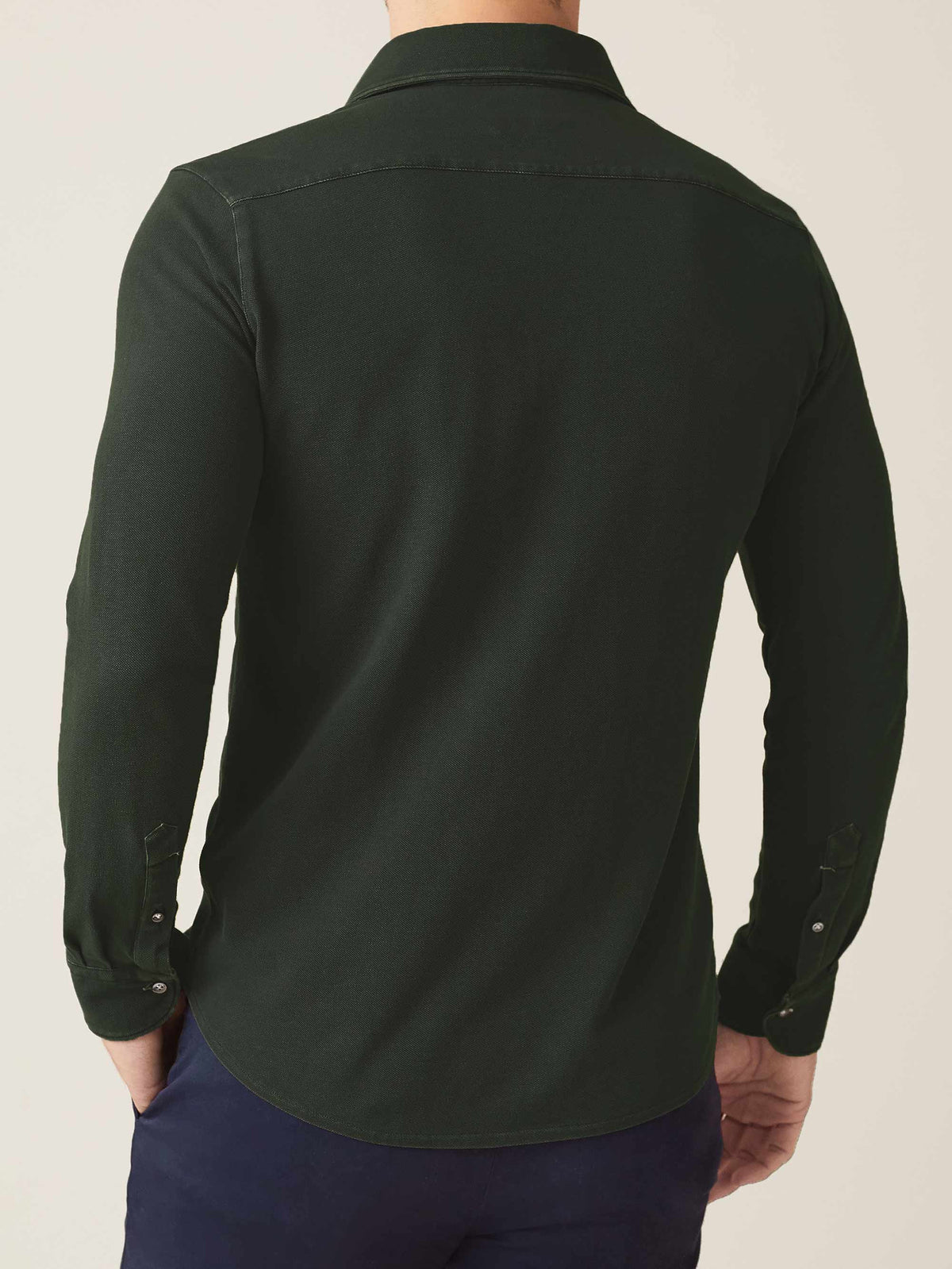 Model seen from behind wearing the Siena Piqué Shirt in forest green, showcasing the relaxed fit and rounded hem.