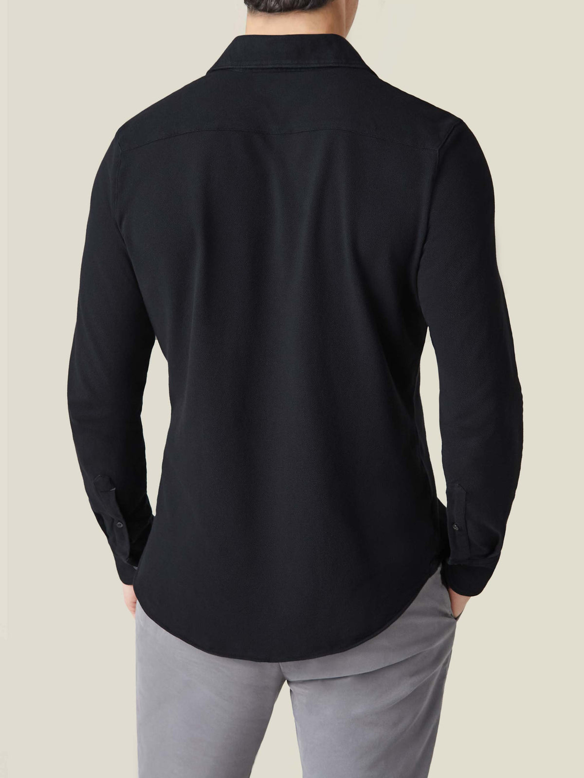 Back view of a model wearing the black Siena Piqué Shirt, showing the relaxed fit and rounded hemline.