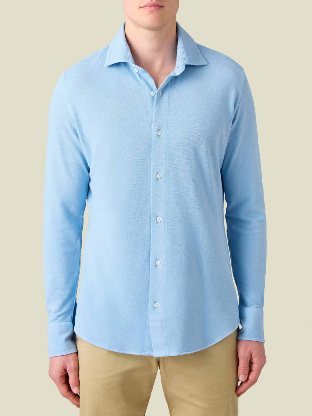 Front view of a model wearing the Siena Piqué Shirt in light blue, showing its fit, cutaway collar, and rounded hemline.