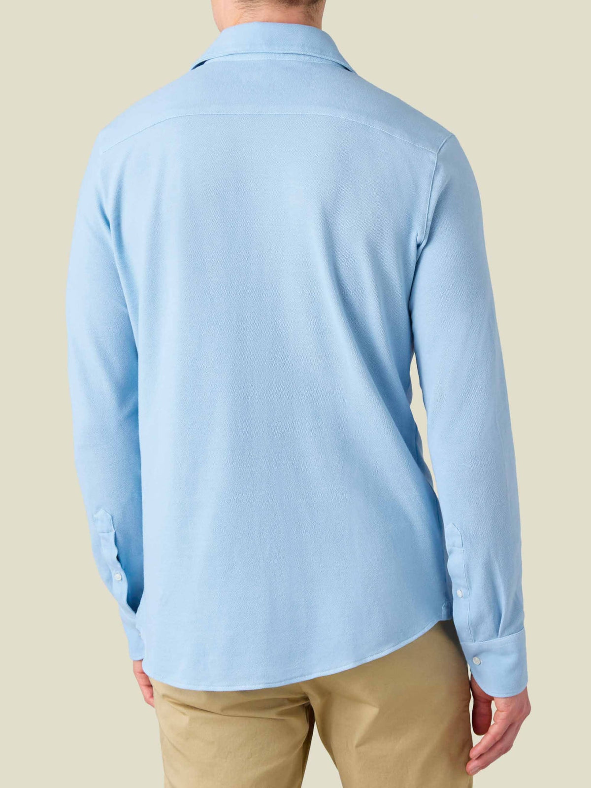 Back view of a model wearing the Siena Piqué Shirt in light blue.