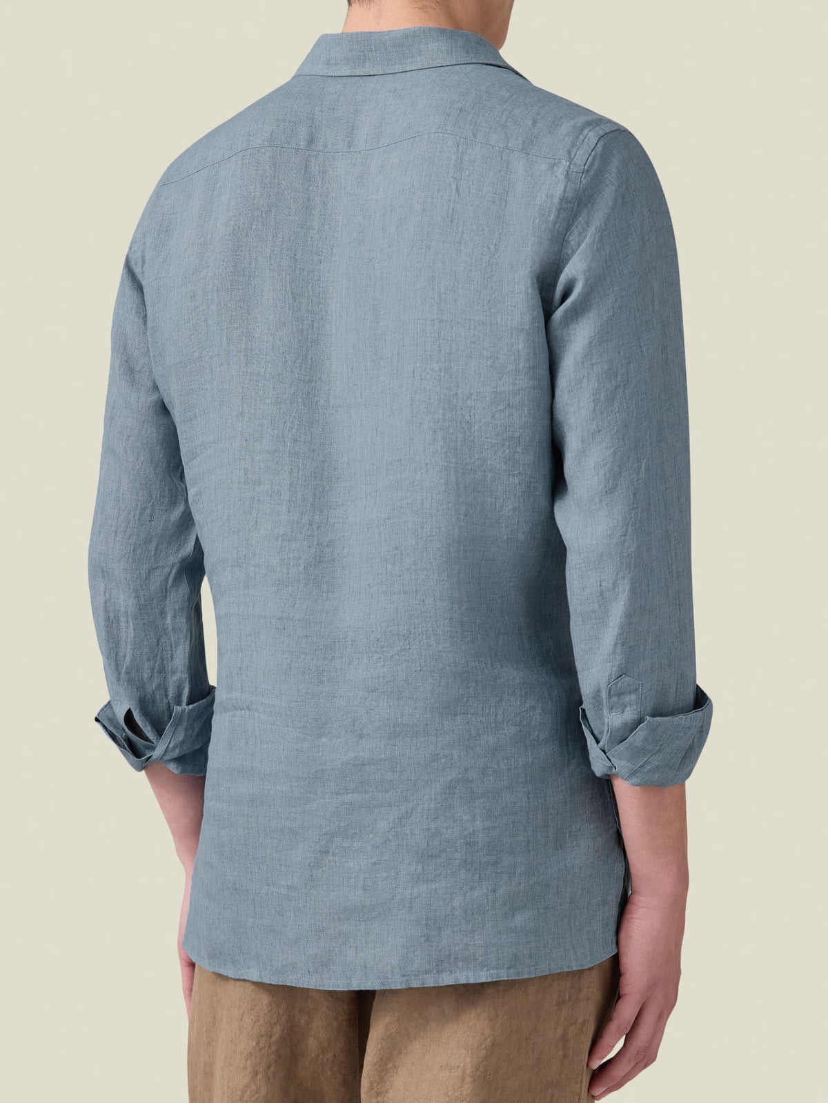 Rear view of a man wearing the French Blue Ravello Linen Shirt with sleeves rolled up to show the relaxed fit.