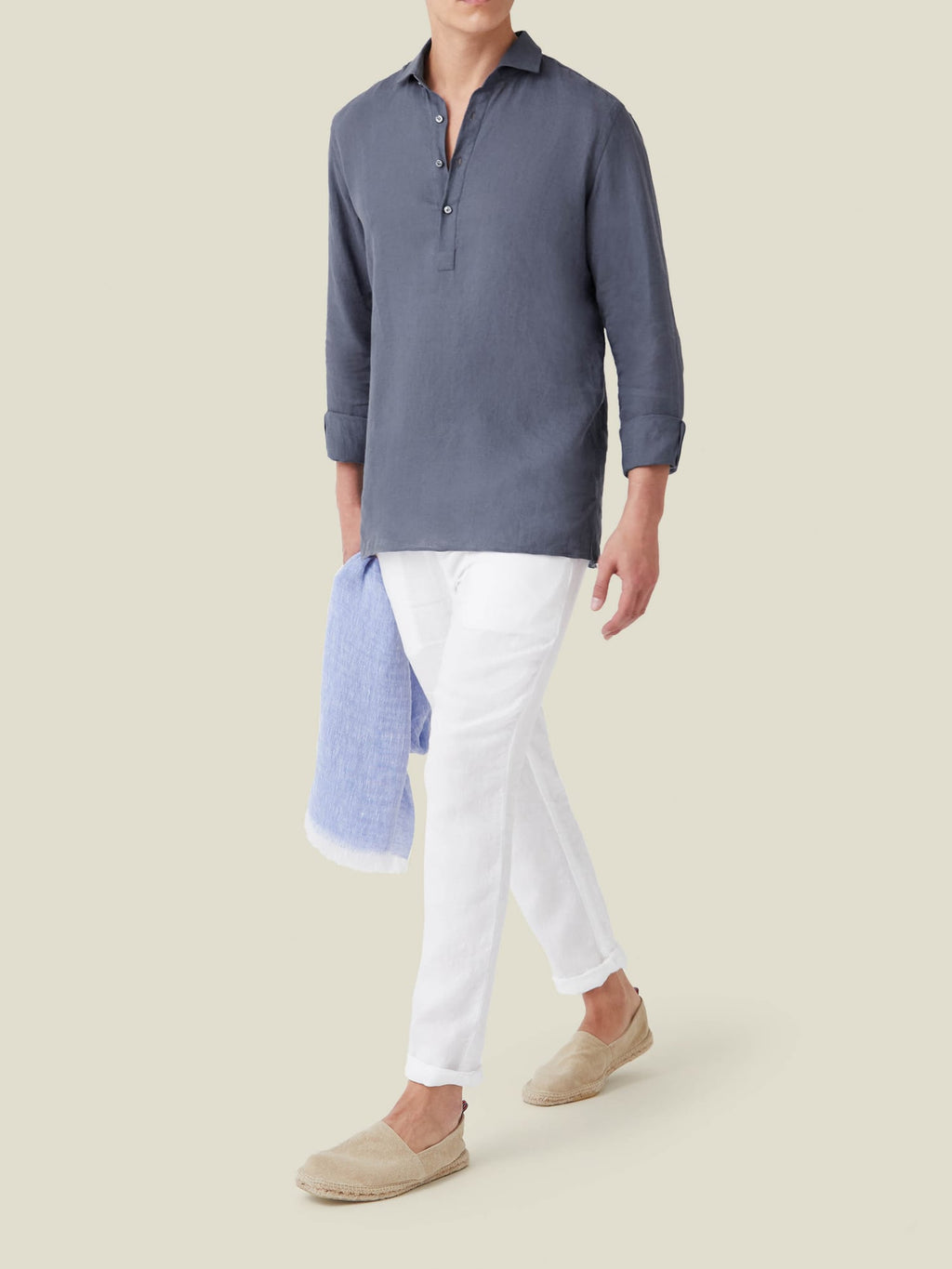 A model wears the Payne's Grey Ravello Linen Shirt with white trousers and beige espadrilles against a neutral background.