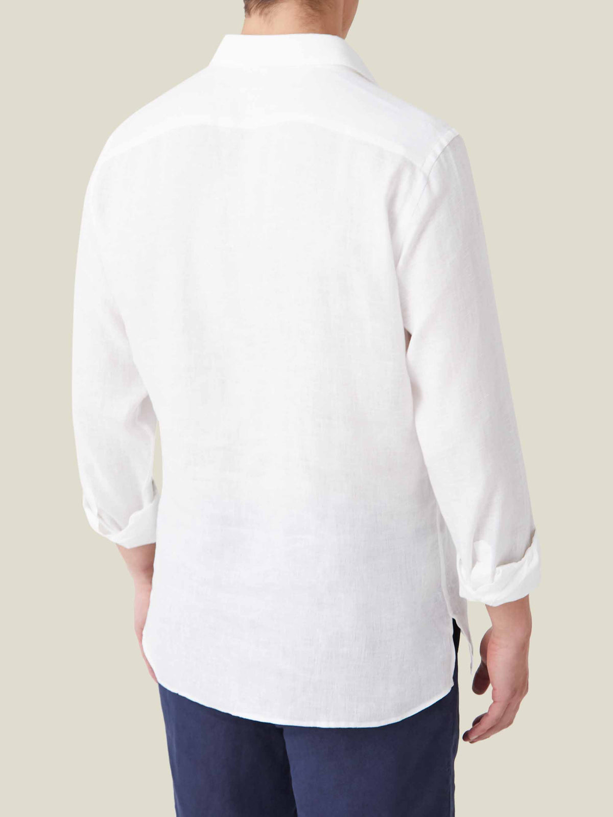 Back view of the Ravello Linen Shirt in white, styled with rolled-up sleeves and paired with navy trousers.