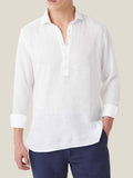 Front view of a model wearing the white Ravello popover linen shirt with rolled-up sleeves and navy trousers.