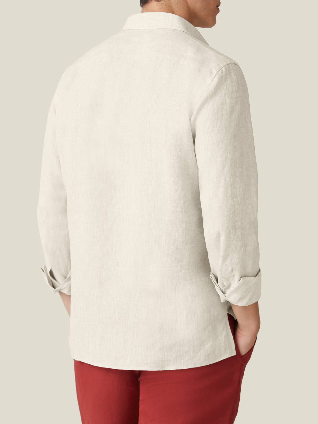 Back view of a man wearing the Sand Ravello Linen Shirt with rolled-up sleeves and red trousers.