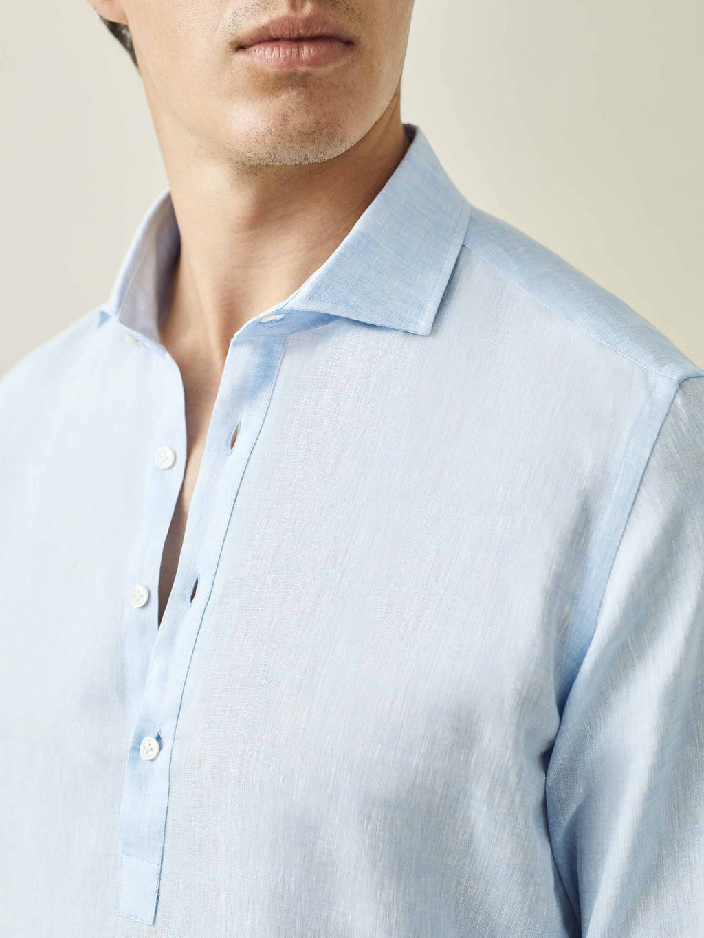 Close-up of a model wearing the sky blue Ravello Linen Shirt, showing the cutaway collar and popover placket.