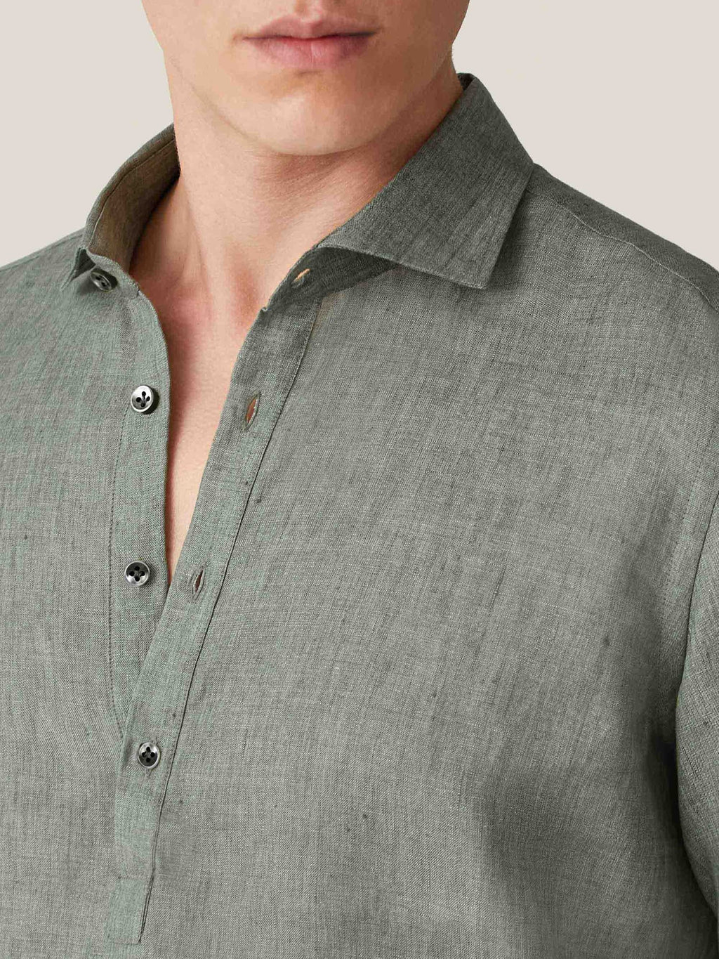 Close-up of the safari green Ravello Linen Shirt, highlighting the cutaway collar, popover placket, and pearl buttons.