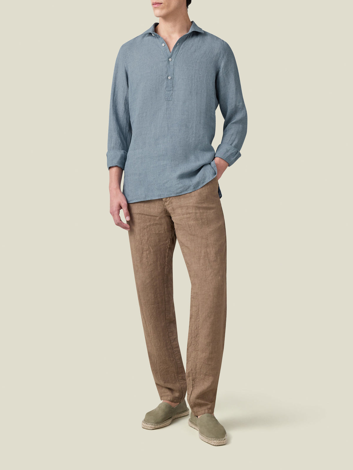 A full view of a model wearing the French Blue Ravello Linen Shirt, paired with brown linen trousers and espadrilles.