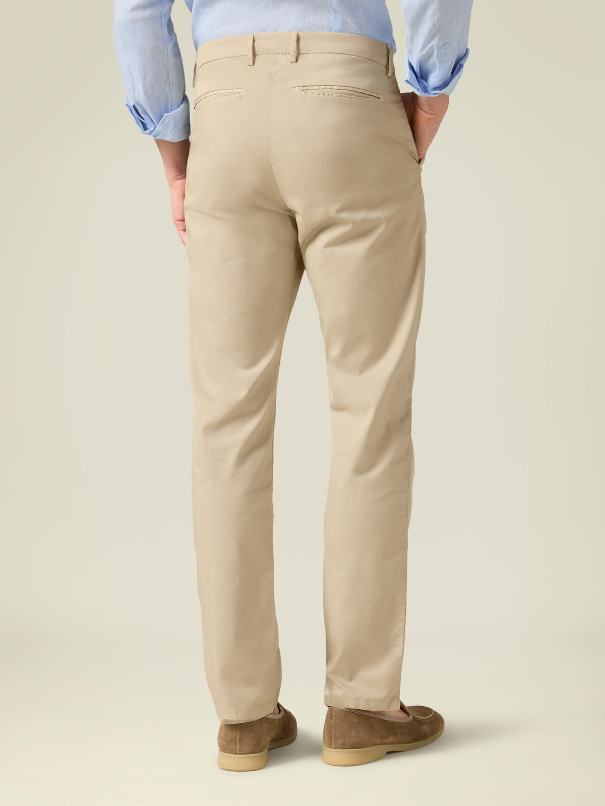 Back view of a man wearing cream Lightweight Cotton Chinos from Luca Faloni, showcasing the fit and rear pocket details.