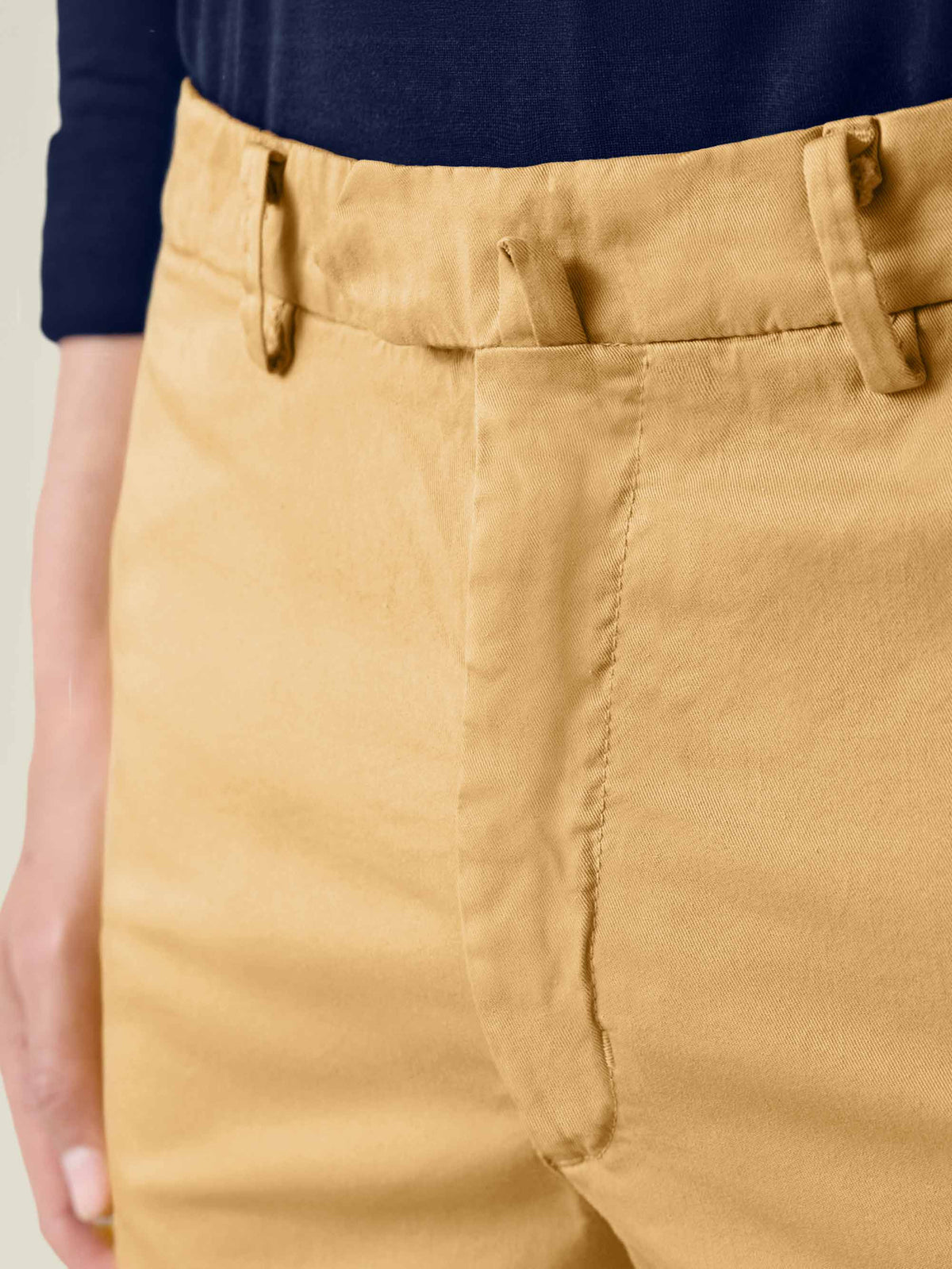 A close-up of the Lightweight Cotton Chinos in mustard, highlighting the waistband, belt loops, and central belt fastener.