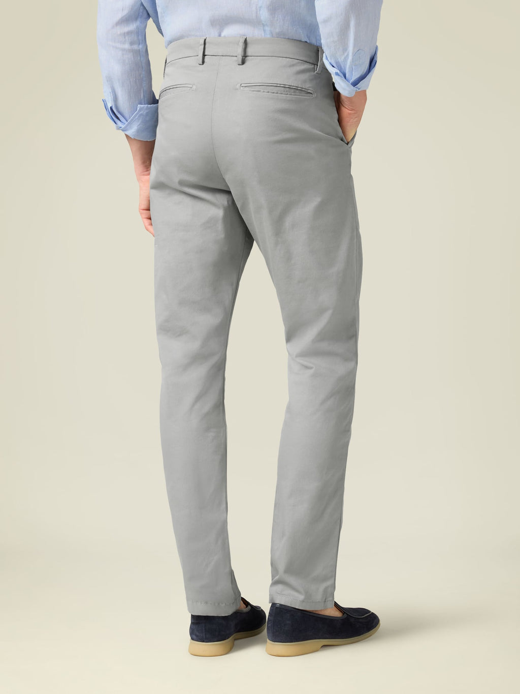 Rear view of a model wearing Luca Faloni's Light Grey Lightweight Cotton Chinos, showing the tapered fit and back pockets.