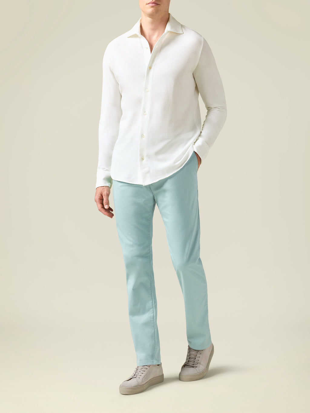 Front view of a model wearing Luca Faloni's Turquoise Lightweight Cotton Chinos with a white shirt and grey sneakers.