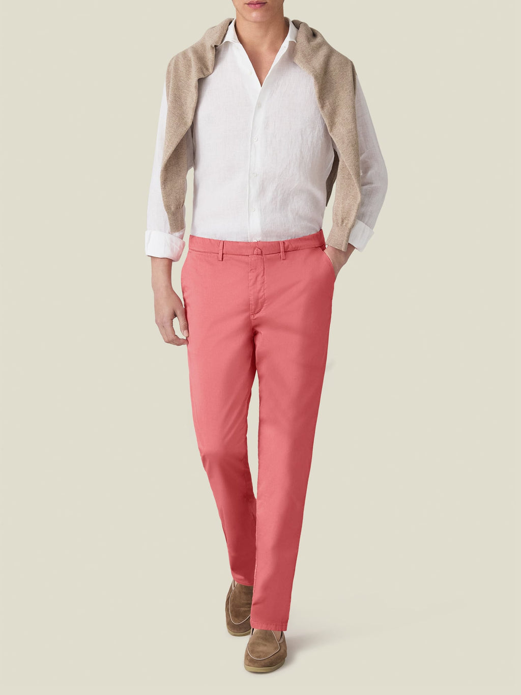 A man models the Strawberry Lightweight Cotton Chinos, styled with a white shirt, beige sweater, and brown loafers.