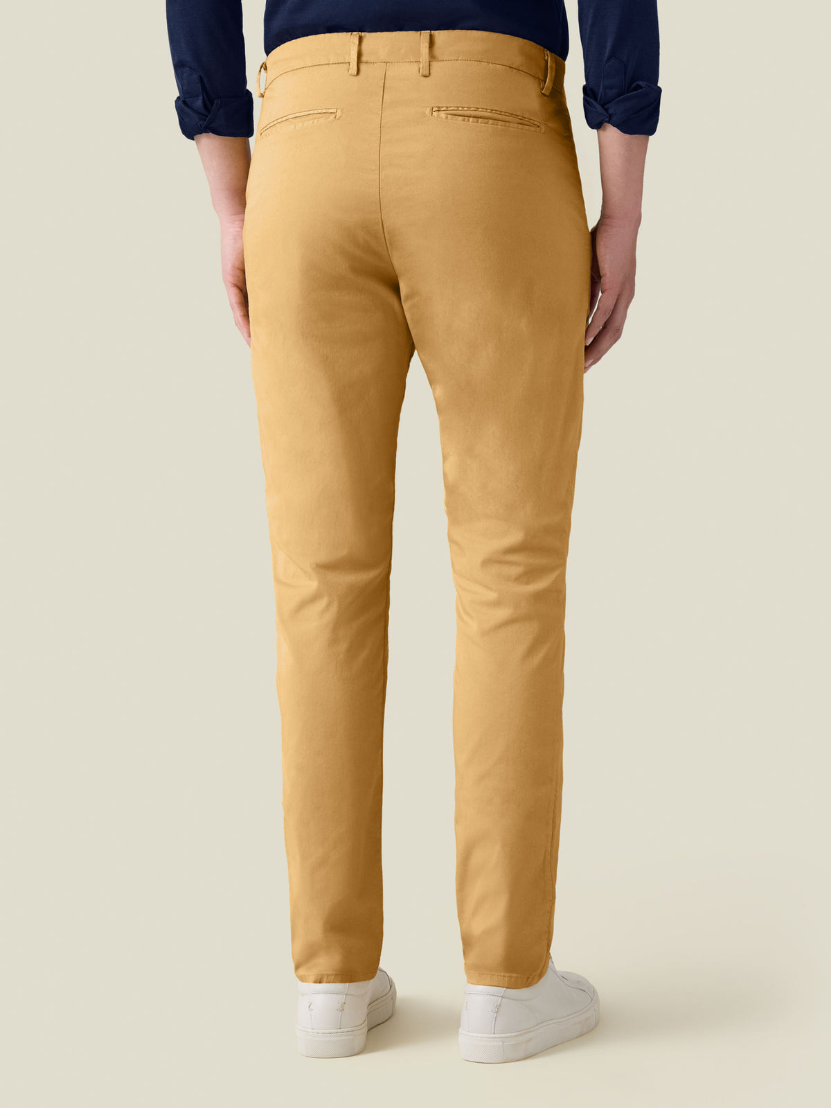 Back view of a model wearing the Mustard Lightweight Cotton Chinos, styled with a navy shirt and white sneakers.