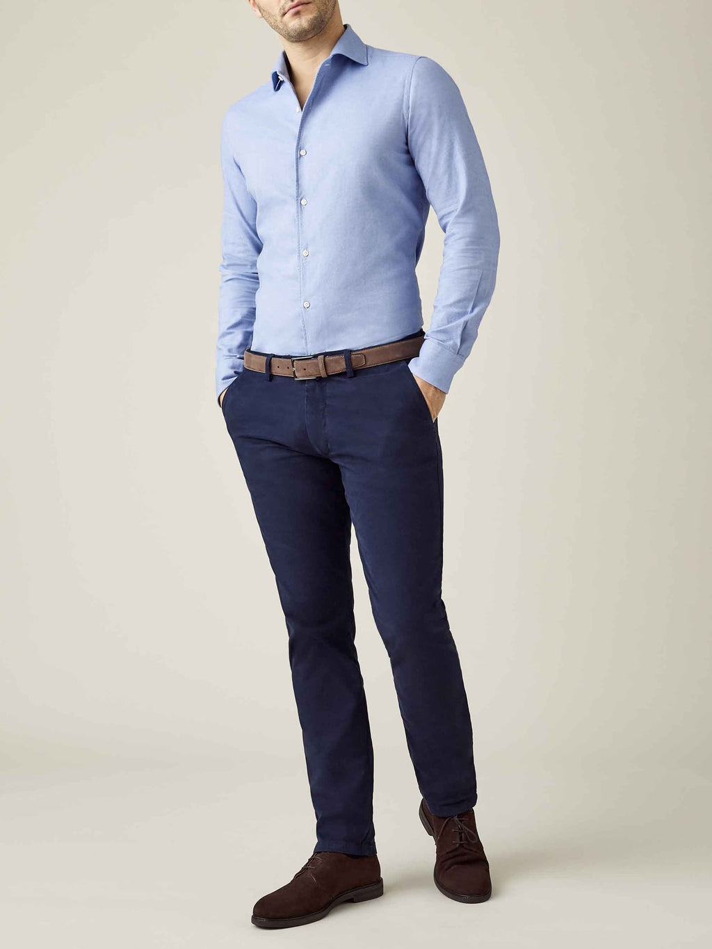 A model wears the Navy Blue Cortina Cotton Chinos with a light blue shirt, a brown belt, and matching dark brown shoes.