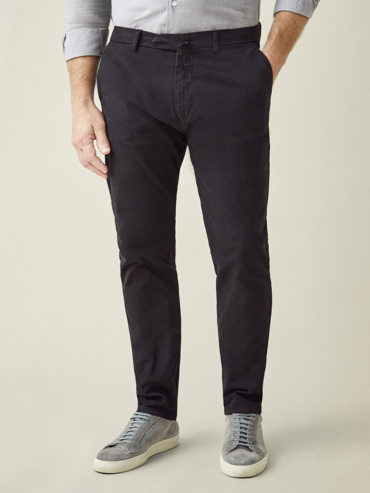 A model showcases the tapered fit of the Black Cortina Cotton Chinos, styled with a grey shirt and matching sneakers.