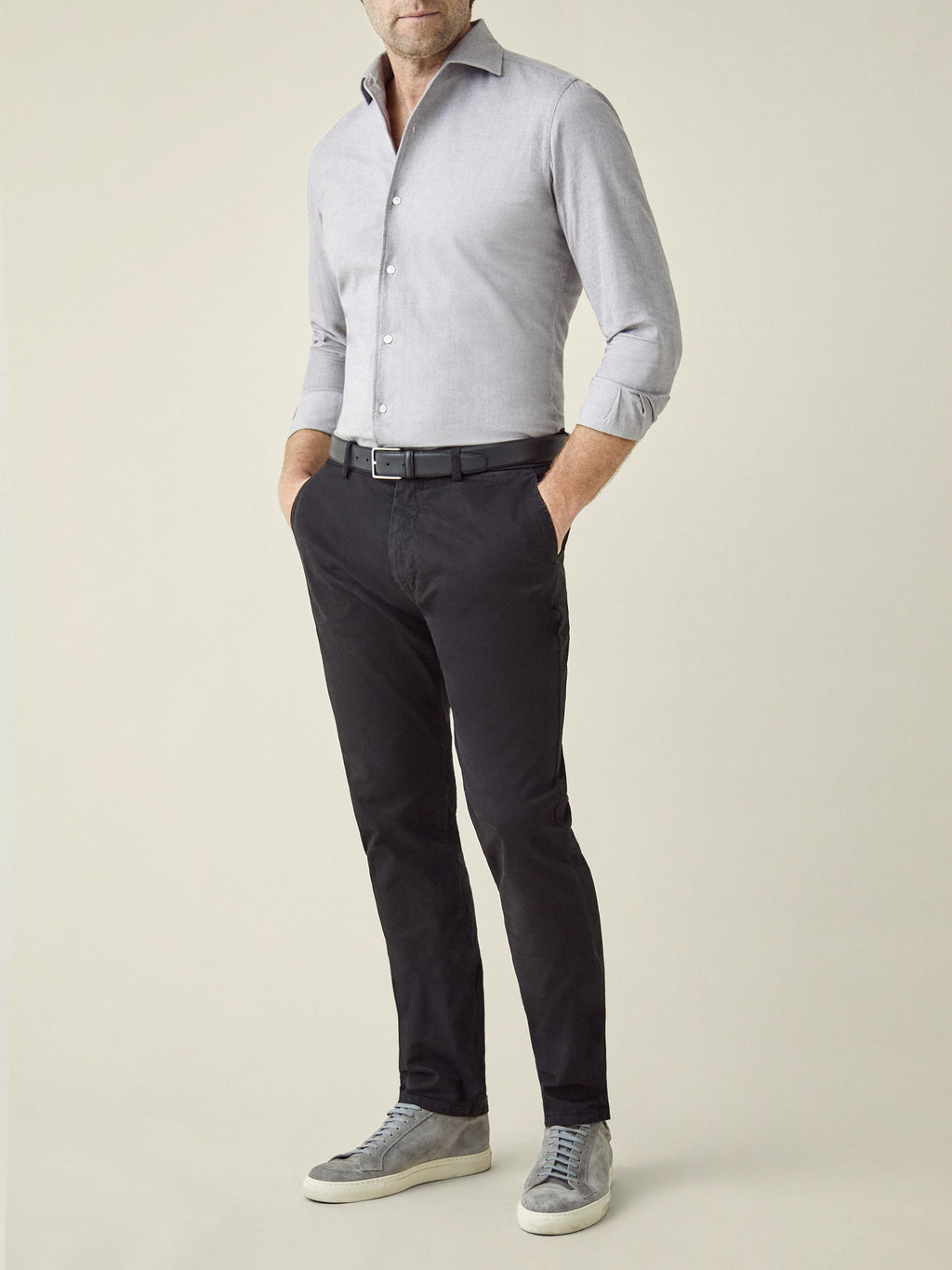 Full-length view of a model wearing the black Cortina Cotton Chinos styled with a light grey shirt and grey sneakers.