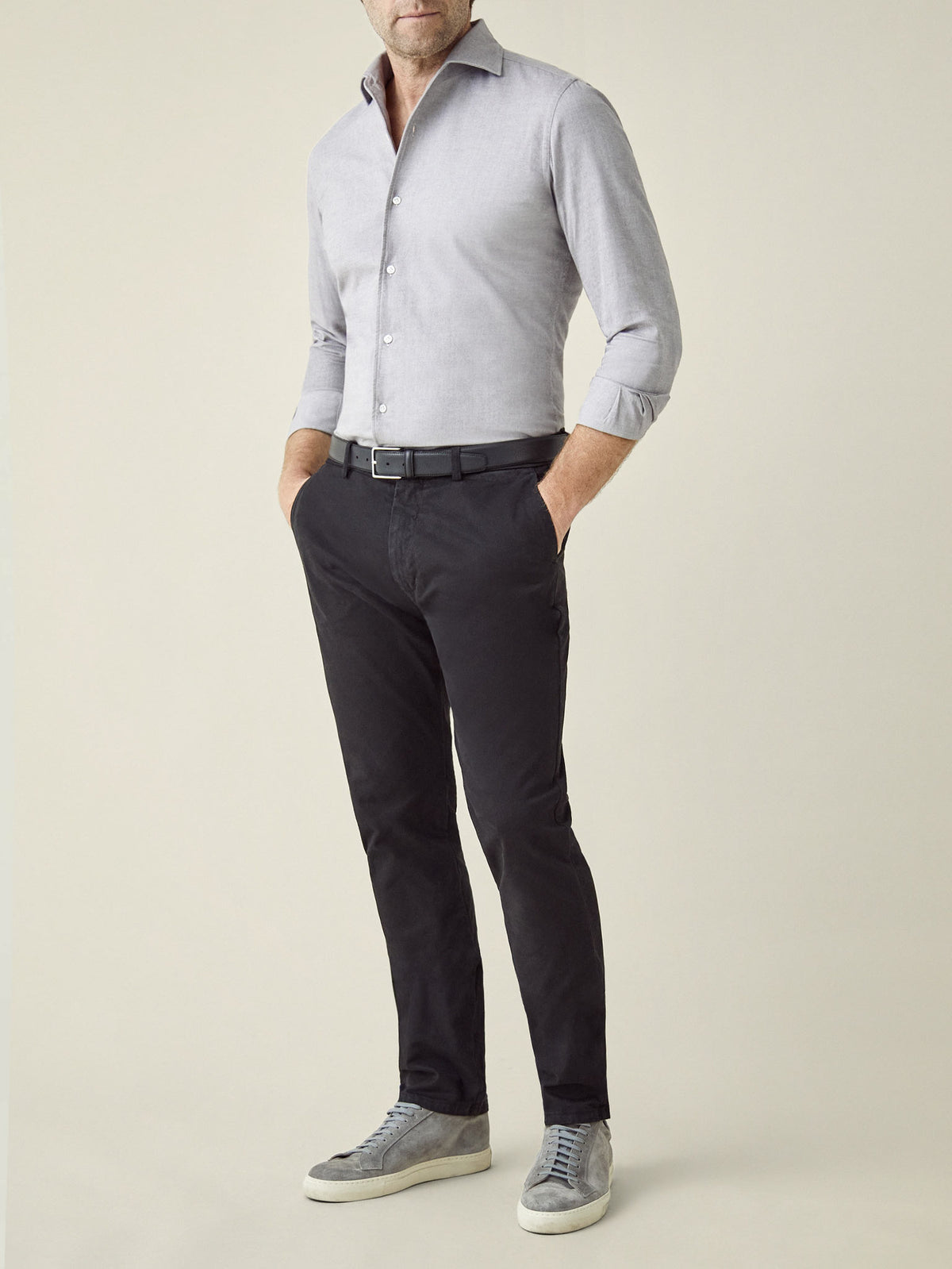 Full-length view of a model wearing the black Cortina Cotton Chinos styled with a light grey shirt and grey sneakers.