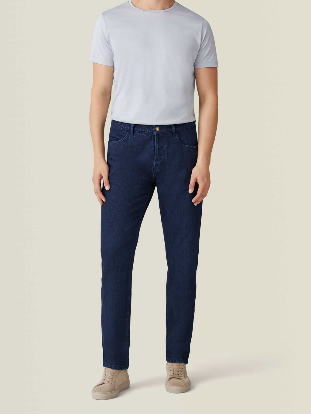 Front view of a model wearing Luca Faloni's Dark Blue Jeans with a light grey t-shirt and beige sneakers.