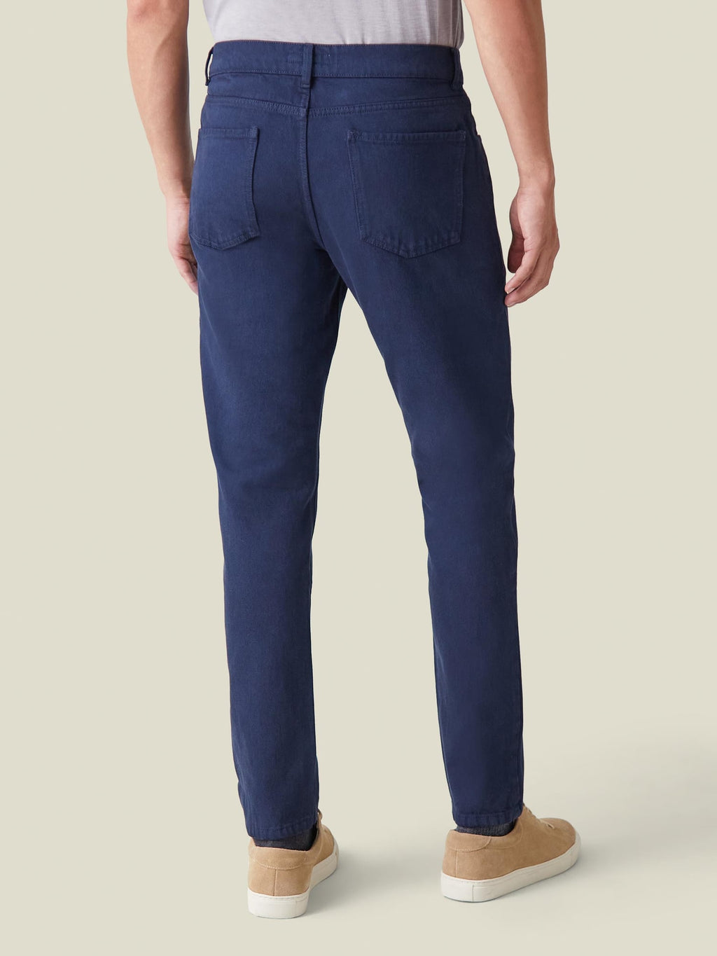 Back view of a model wearing Luca Faloni's Classic Blue tapered jeans, showcasing the fit and clean, rivetless design.