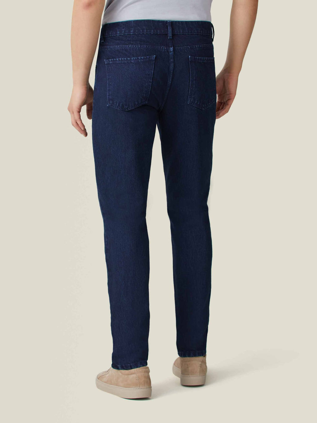 Back view of a man wearing Luca Faloni's dark blue tapered jeans, highlighting the clean fit and rivetless design.