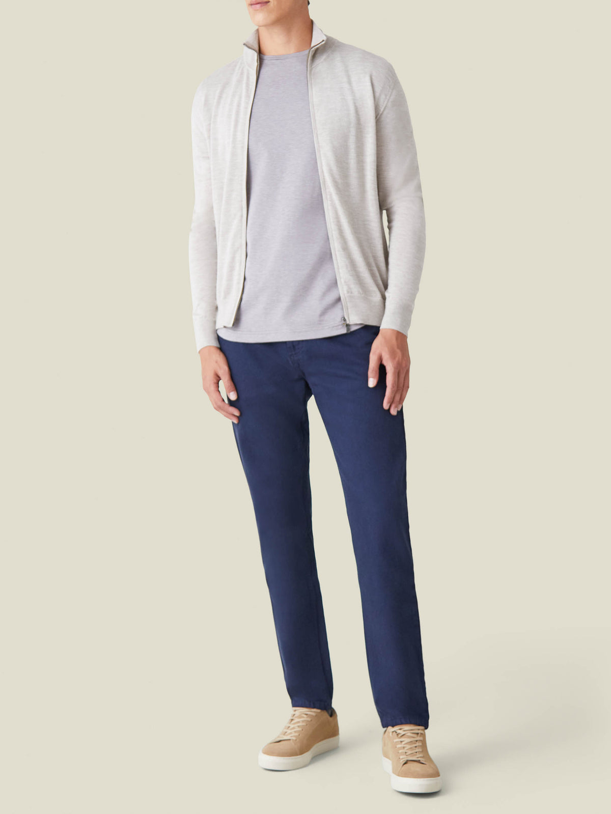 A model wears the Luca Faloni Jeans in Classic Blue, styled with a grey t-shirt, a light grey zip cardigan and tan sneakers.