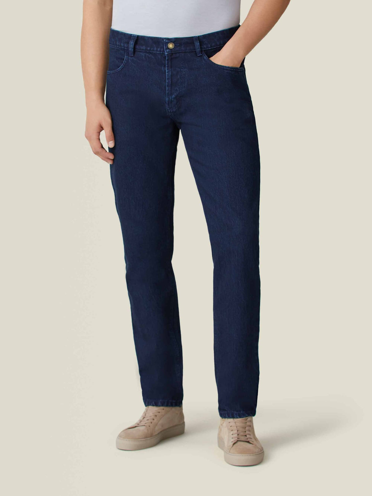 Front view of a model wearing Luca Faloni's dark blue tapered jeans with a white t-shirt and beige sneakers.