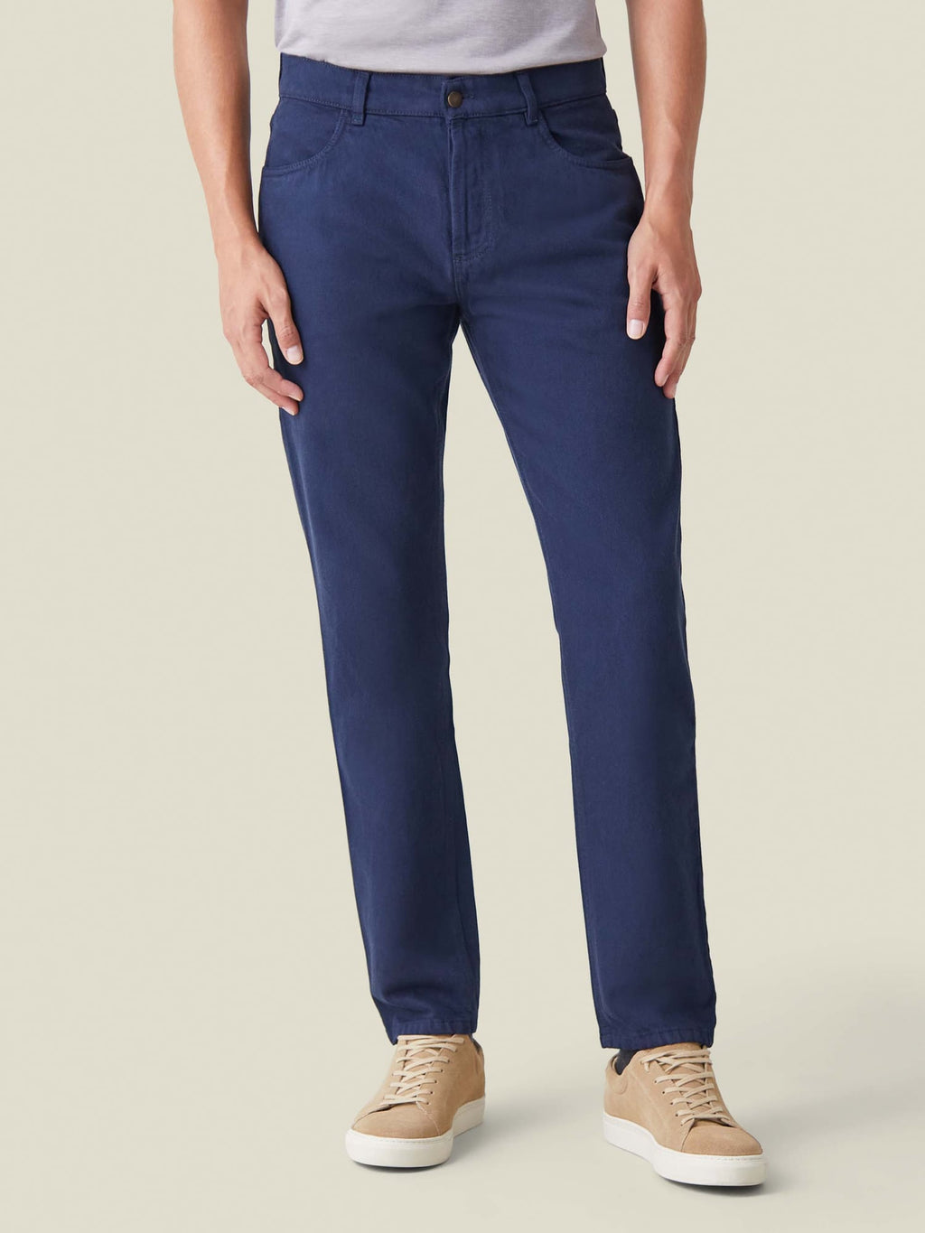 Front view of a model wearing Luca Faloni's Tapered Fit Jeans in Classic Blue, styled with a grey t-shirt and beige sneakers.