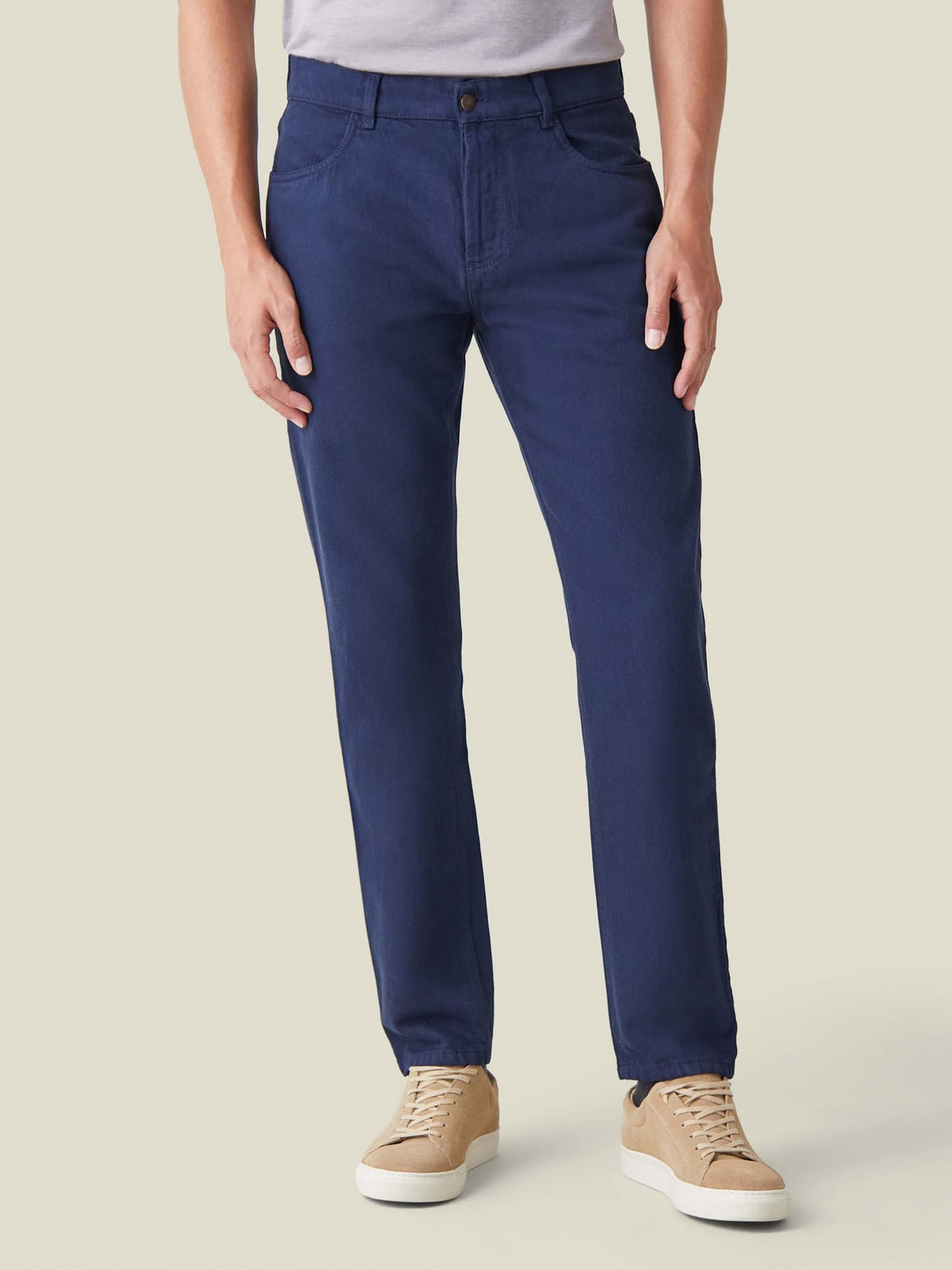 Front view of a model wearing Luca Faloni's Tapered Fit Jeans in Classic Blue, styled with a grey t-shirt and beige sneakers.