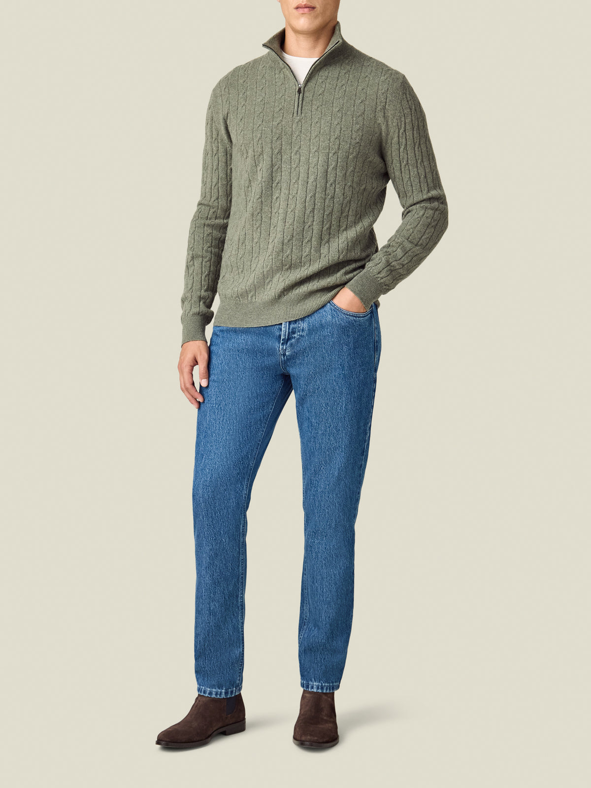 Front view of a model wearing the Luca Faloni Jeans in classic blue, styled with a green sweater and brown boots.