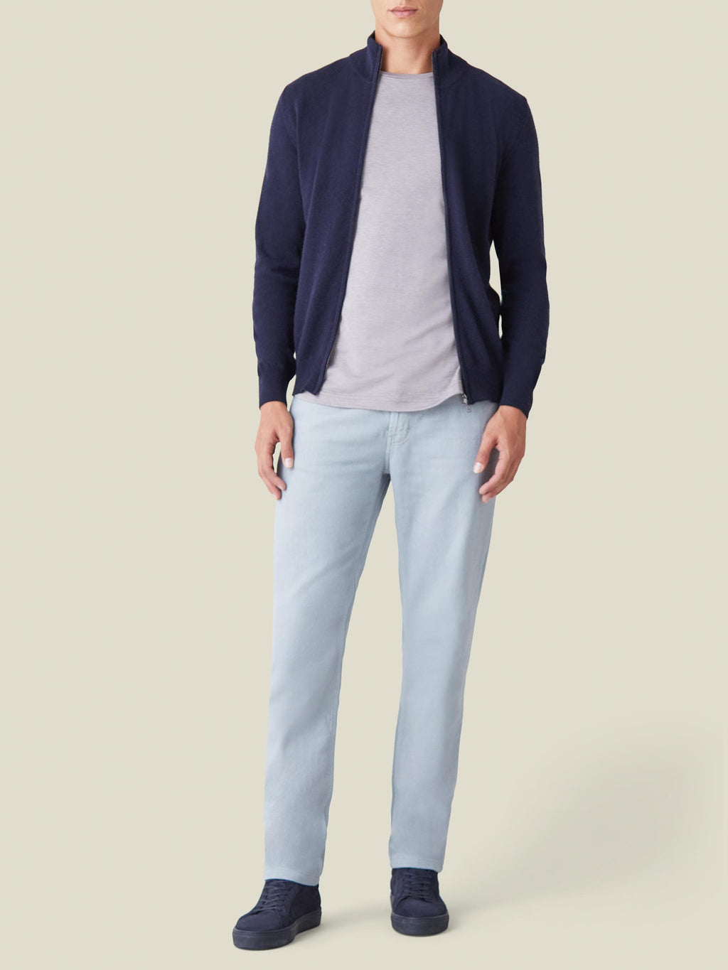 Front view of a model wearing Luca Faloni's light grey jeans with a grey t-shirt, navy zip cardigan and navy sneakers.