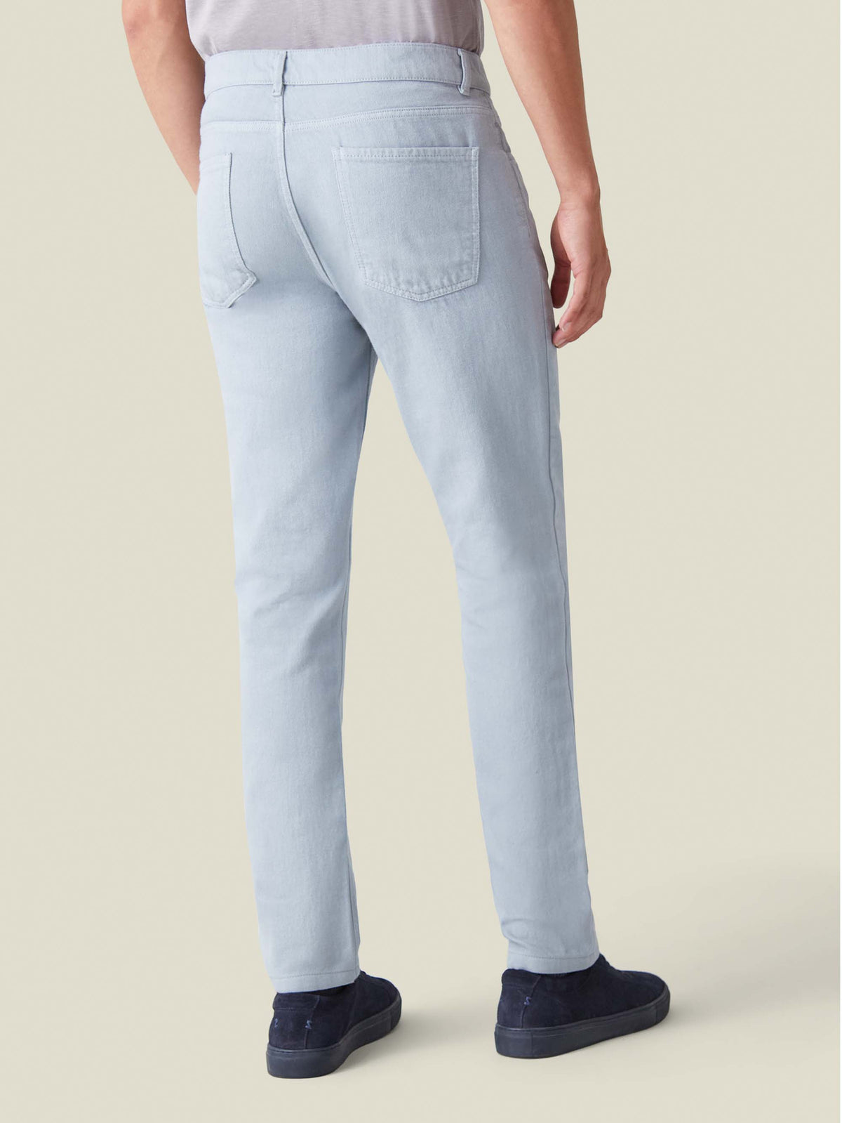Back view of a model wearing Luca Faloni's light grey tapered jeans, showcasing the fit and back pocket design.