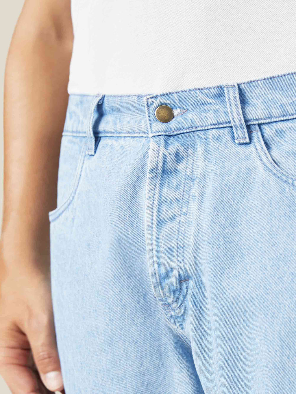 A close-up of the front of Luca Faloni's light blue jeans, focusing on the button fly, waistband, and pocket detail.