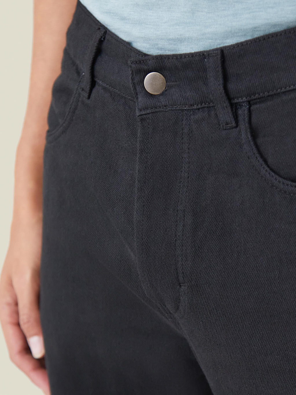 Close-up on the rivetless button closure of the Luca Faloni black denim jeans.