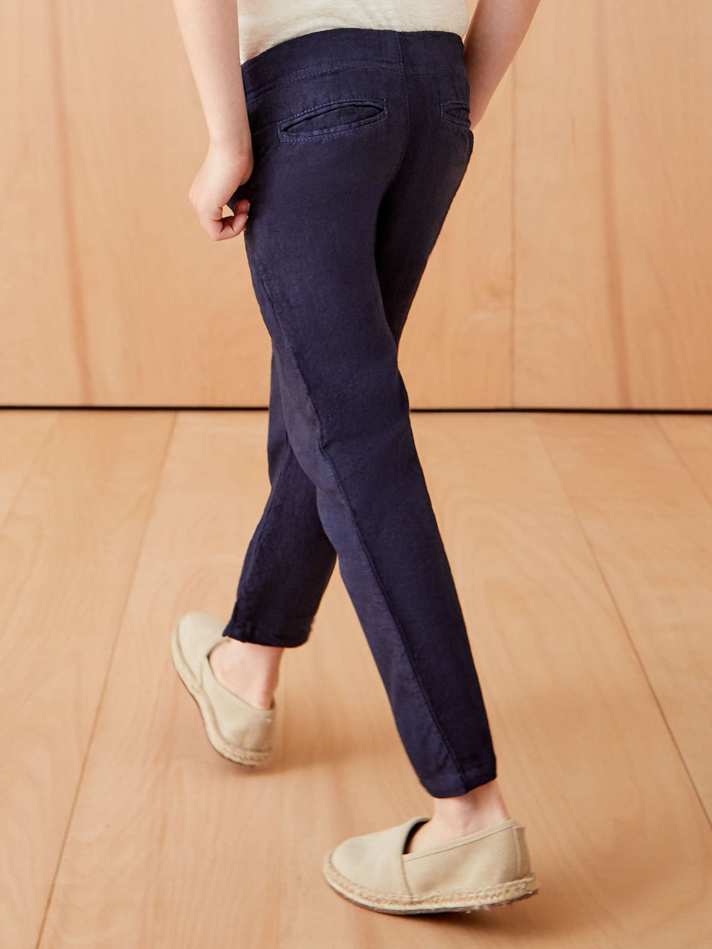 A back view of a child wearing the navy blue Lipari Junior Linen Trousers, showcasing the tapered fit and back pockets.