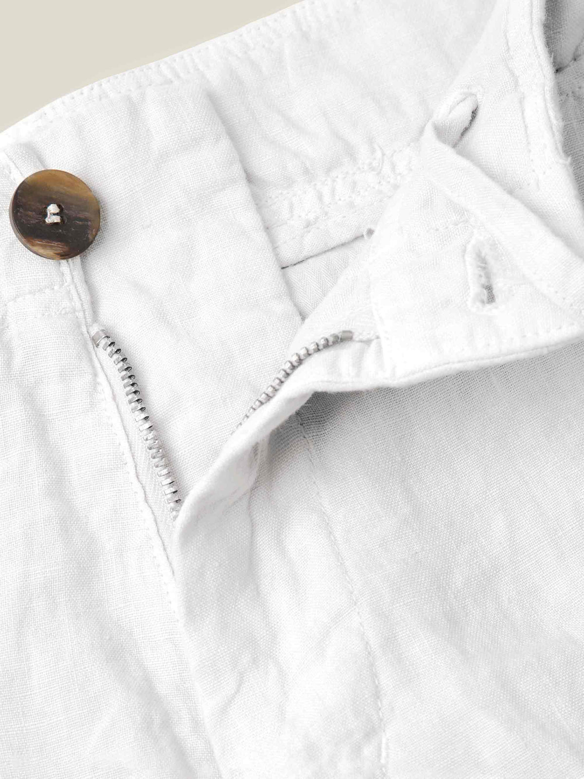 Close-up of the traditional horn button and zip fly on the white Lipari Linen Trousers.