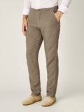 Side view of a man wearing the Lipari Linen Trousers in hazelnut brown, paired with a pink shirt and beige espadrilles.