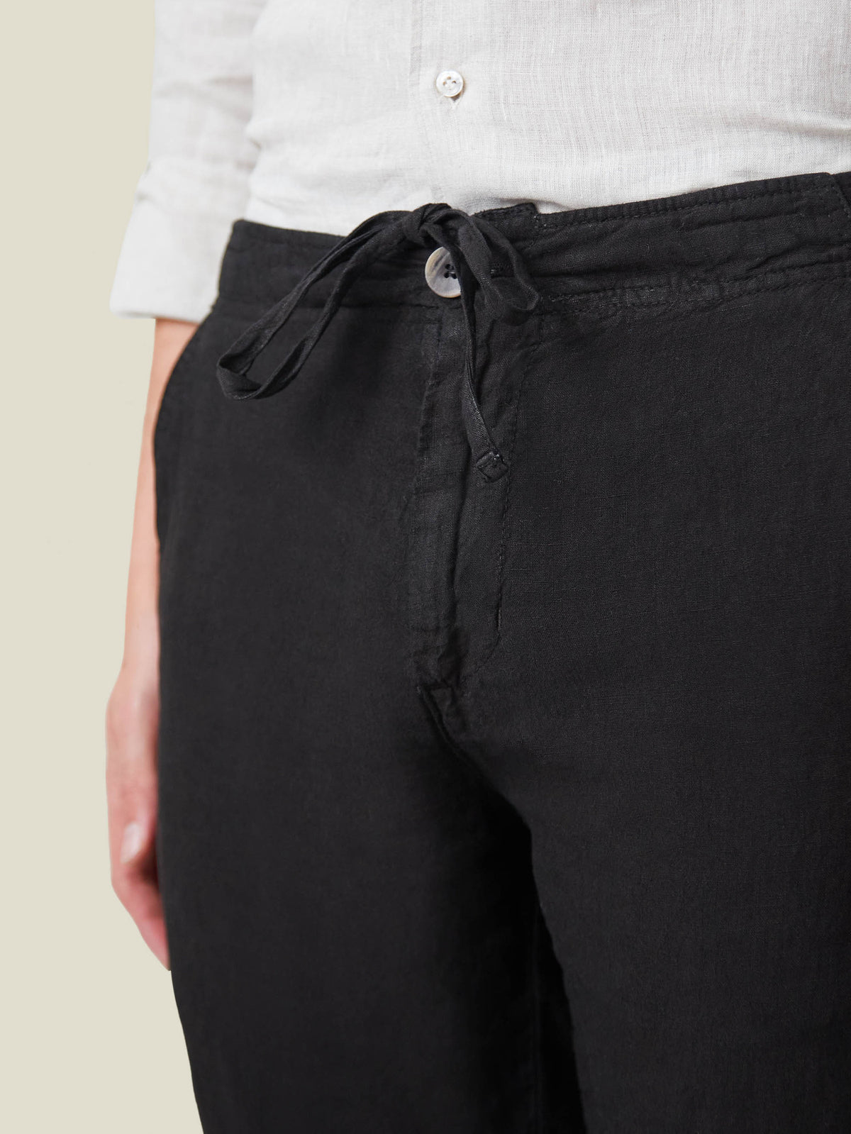 Close-up detail of the black Lipari Linen Trousers, showcasing the drawstring and horn button closure at the waist.