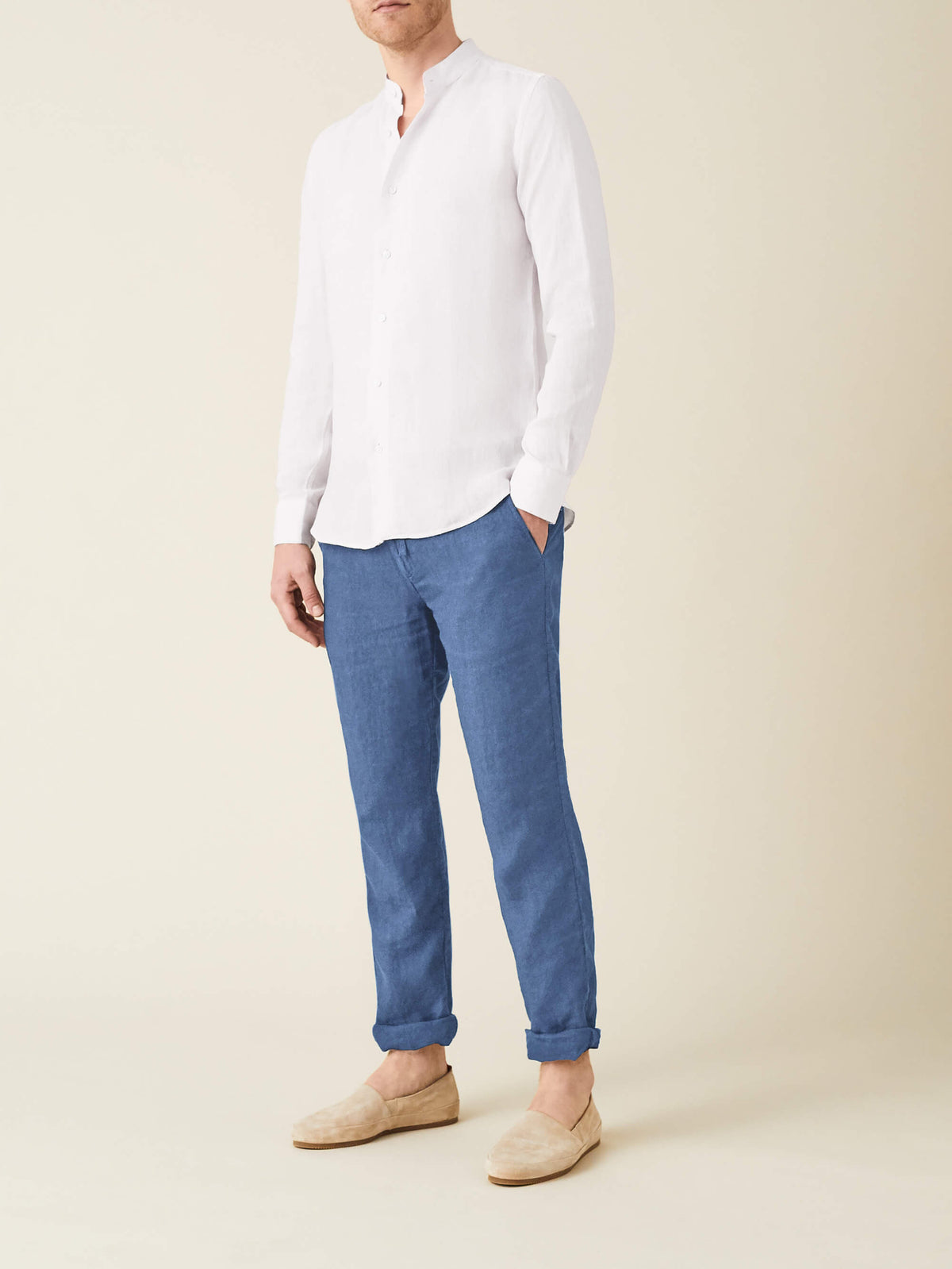 A man models the Luca Faloni Lipari Linen Trousers in Capri Blue, paired with a white linen shirt and beige loafers.