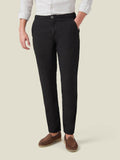 A model wears the Lipari Linen Trousers in black, paired with a white linen shirt and brown suede loafers.