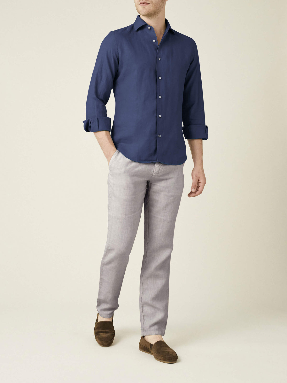 A model wears the Luca Faloni Lipari Linen Trousers in Light Grey, styled with a navy shirt and brown suede loafers.