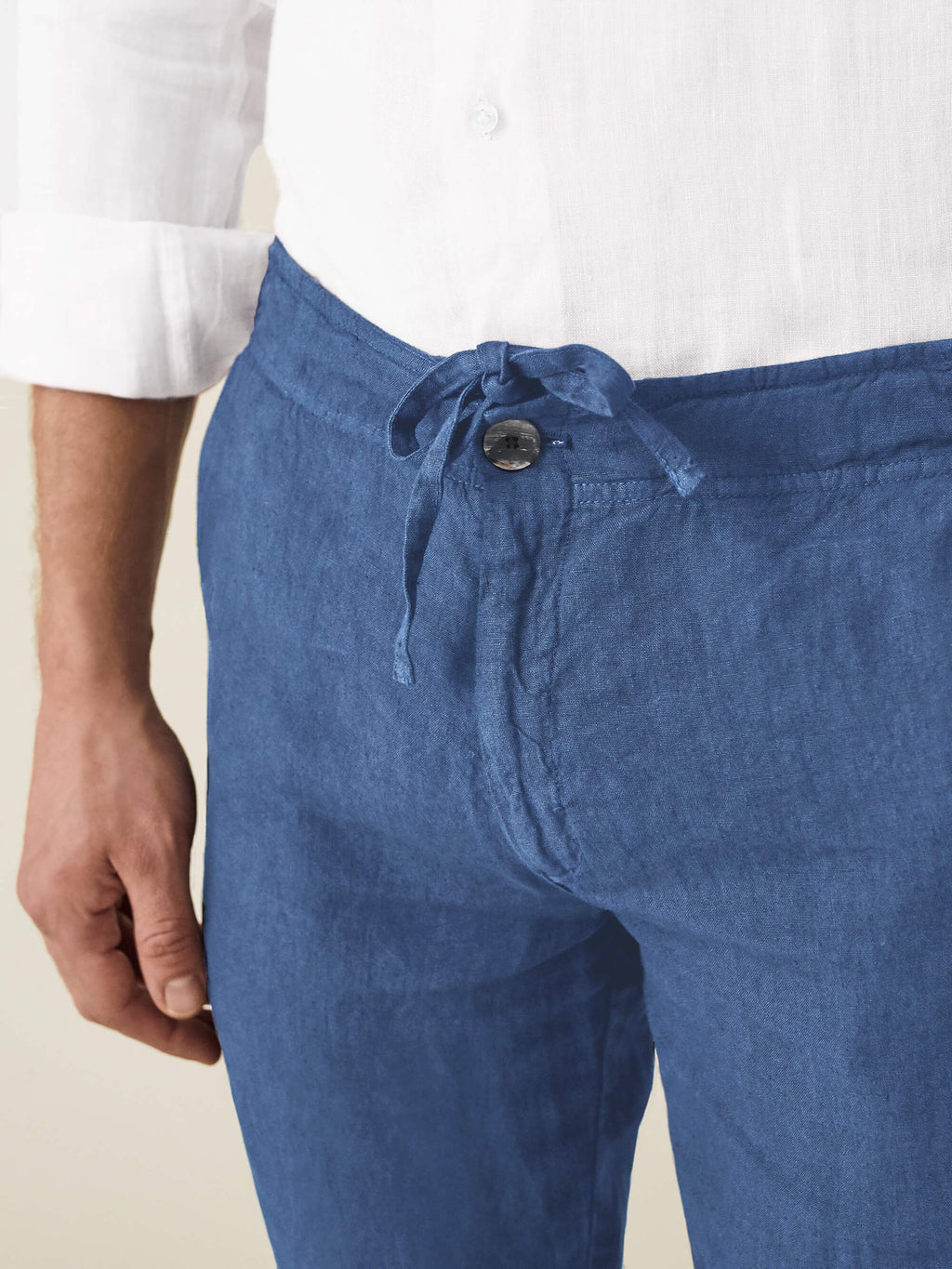 Close-up of a model wearing the Capri Blue Lipari Linen Trousers, highlighting the drawstring and button fly.