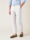 Side view of a man wearing the white Lipari linen trousers with rolled cuffs, paired with a blue shirt and green loafers.