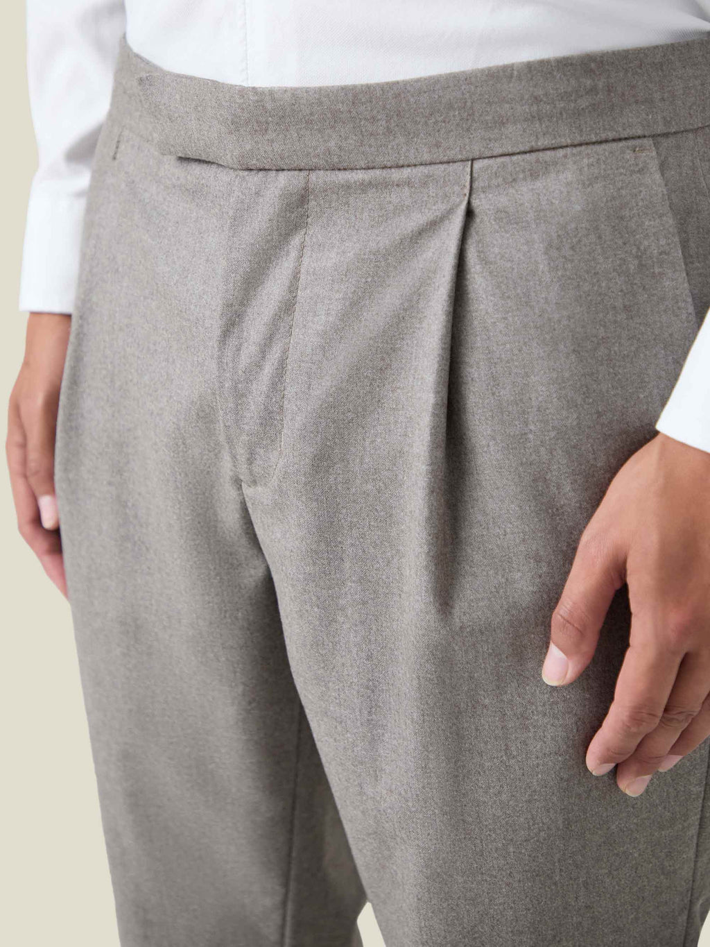 A detailed close-up of the single front pleat and waistband on the Camel Beige Wool Pleated Trousers.