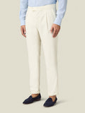 Side view of a model wearing the Luca Faloni Wool Pleated Trousers in ivory with a light blue shirt and navy loafers.